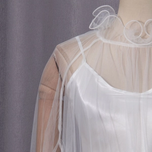 Close-up of elegant double-layer white blouse with delicate lace collar and mesh texture