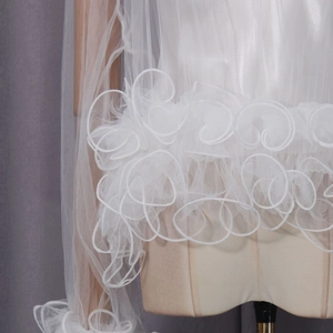 Detail view of white mesh shawl with 3D spiral ruffle trim and layered texture
