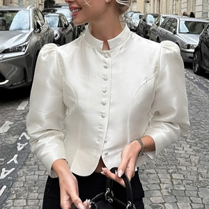 Close-up of white satin blouse featuring a mandarin collar and elegant pearl-like buttons