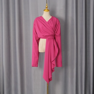Detail of fuchsia long-sleeve wrap top with elegant side draping and deep V-neckline