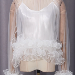 Detailed view of white mesh blouse featuring tiered ruffles and lace patchwork design