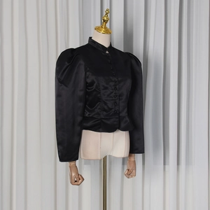 Detail of black satin blouse featuring puff sleeves, stand collar, and button-up front design