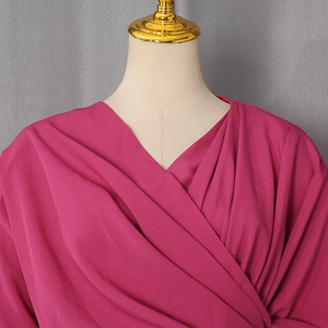 Detail of elegant magenta blouse featuring a crisscross V-neckline and draped pleated fabric