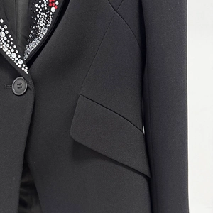 Detail of elegant black blazer collar featuring hand-set red and white rhinestones
