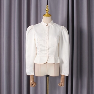 Detail of elegant cream satin blouse featuring puff sleeves and peplum waist design