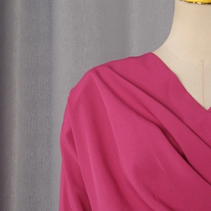 Close-up of elegant V-neck drape and silky magenta fabric texture on a mannequin