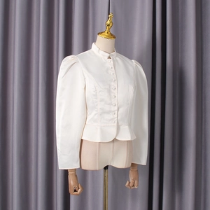 Detail view of white satin shirt featuring mock neck with rows of buttons and ruffled hem