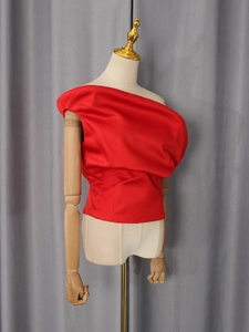 Dettaglio del top monospalla in raso rosso con pieghe drammatiche e vita a corsetto