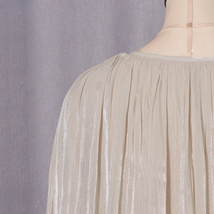 Detailed macro view of the pleated champagne satin fabric texture on the elegant shirt