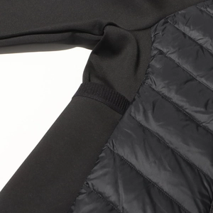 Close-up of black quilted down jacket with functional mixed-fabric sleeve stitching details