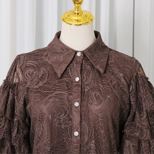 Detail of brown lace shirt featuring rose patterns and decorative rhinestone buttons