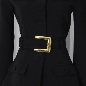 Detail of elegant black blazer featuring a gold square metallic buckle and waist belt