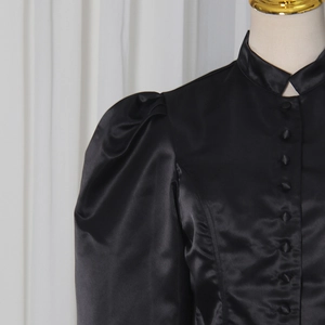 Close-up of black satin long sleeve shirt featuring high collar and delicate covered buttons