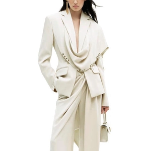 Detail of elegant cream blazer featuring a scarf lapel and gold metal pin decoration