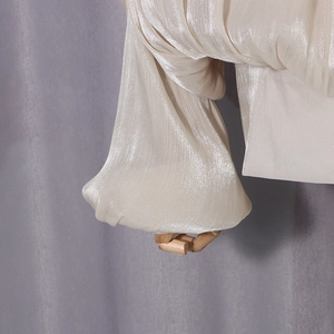 Detailed view of the off-white pearlescent pleated fabric and elegant puff sleeve texture