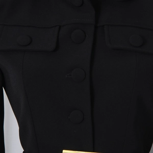 Close-up of black blazer with flap pocket detail and fabric-covered buttons on the suit