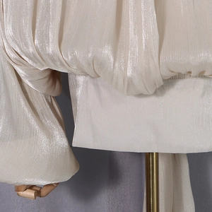 Detail of high-gloss pleated champagne fabric with elegant puff sleeve texture