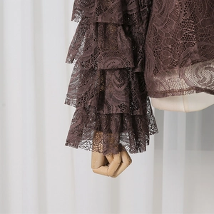 Detailed view of dark brown lace sleeves with layered ruffles and rose patterns