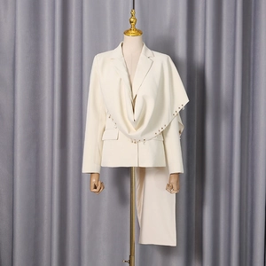 Detail of ivory blazer featuring draped collar with pearl and rhinestone pendants