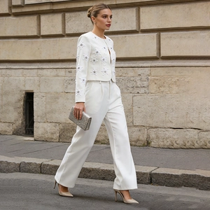 Detail view of white blazer set with 3D floral embellishments and wide leg trousers