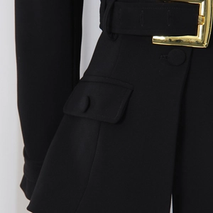 Detail of black blazer featuring a gold polished metal buckle belt and flap pocket
