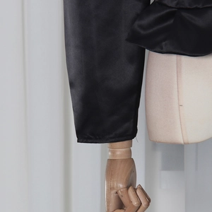 Detailed close-up of black satin shirt cuffs with elegant ruffled edges and glossy finish