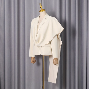 Detail of cream blazer featuring unique asymmetrical shawl with dangling pearl trim