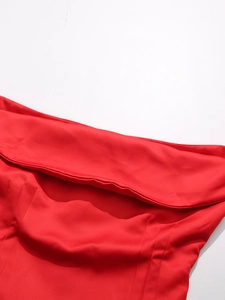 Dettaglio del tessuto satinato rosso con trama liscia e setosa e struttura piegata del top