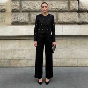 Detail of black stylish suit with starry beaded jacket and wide leg high-waist trousers