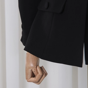 Detail of black blazer featuring sleek cuff straps and a flap pocket with matching button
