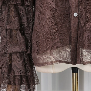Close-up of tiered lace cuffs with rose embroidery and sparkling rhinestone button detail
