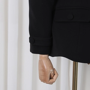 Detailed close-up of a black blazer featuring sleeve cuff straps and a flap pocket design