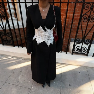 Vue détaillée du manteau noir avec corset en dentelle blanche et motifs floraux