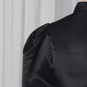 Close-up of black satin puff sleeve detail with soft pleated texture and silk gloss
