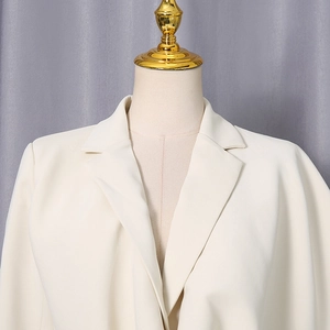 Close-up of beige blazer lapel featuring modern metal ring stitching detail