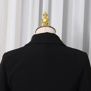 Detail shot of the tailored collar and structured shoulders of a black blazer on mannequin