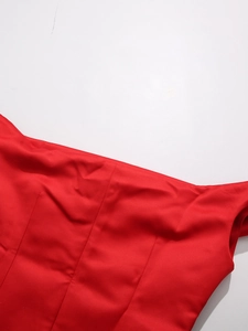 Dettaglio ravvicinato del tessuto satinato rosso con cuciture verticali di un top