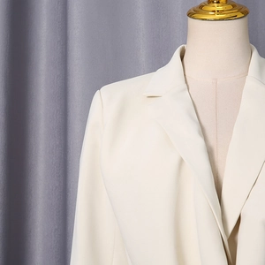Detail of cream white blazer featuring notched lapels and fine twill fabric texture