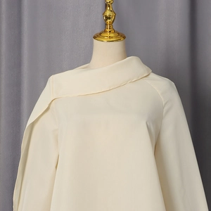 Close-up of beige blouse featuring elegant asymmetrical fold collar and draped scarf detail