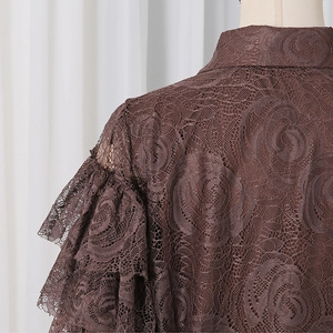 Detailed macro view of dark brown lace fabric with rose patterns and ruffled sleeve layers