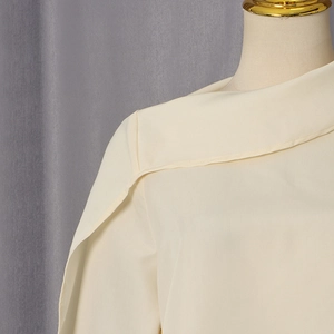 Detail of beige chiffon blouse featuring asymmetric wrap front and elegant shoulder pleats