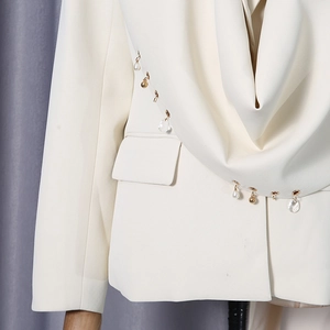 Detail of cream blazer showing draped collar with pearl and golden bead embellishments