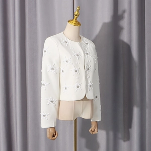 Detailed macro view of white tweed jacket with 3D floral embroidery and rhinestones