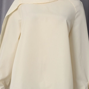 Detailed close-up of cream-beige chiffon blouse fabric texture and clean shoulder stitching