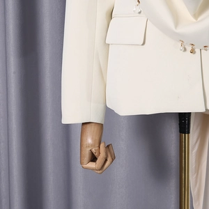 Detail of white blazer sleeves featuring elegant pearl and crystal pendant embellishments