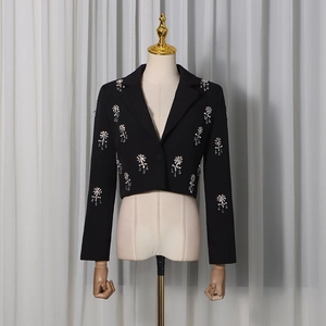 Detail of a black cropped blazer featuring intricate rhinestone flower embellishments