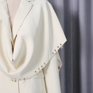 Detail of metal eyelets and pearl pendants on the cream shawl blazer jacket