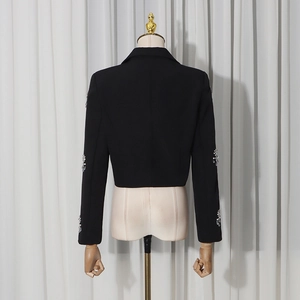 Detail of black fitted blazer featuring luxury rhinestone embellishments on the sleeves