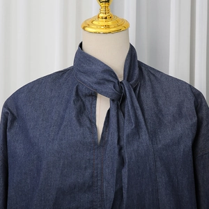 Close-up of navy denim top featuring contrast stitching and bow tie neck detail