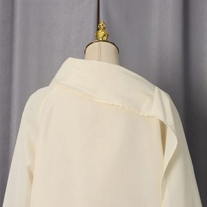 Detail showing the elegant criss-cross back design and flowing beige chiffon shirt fabric